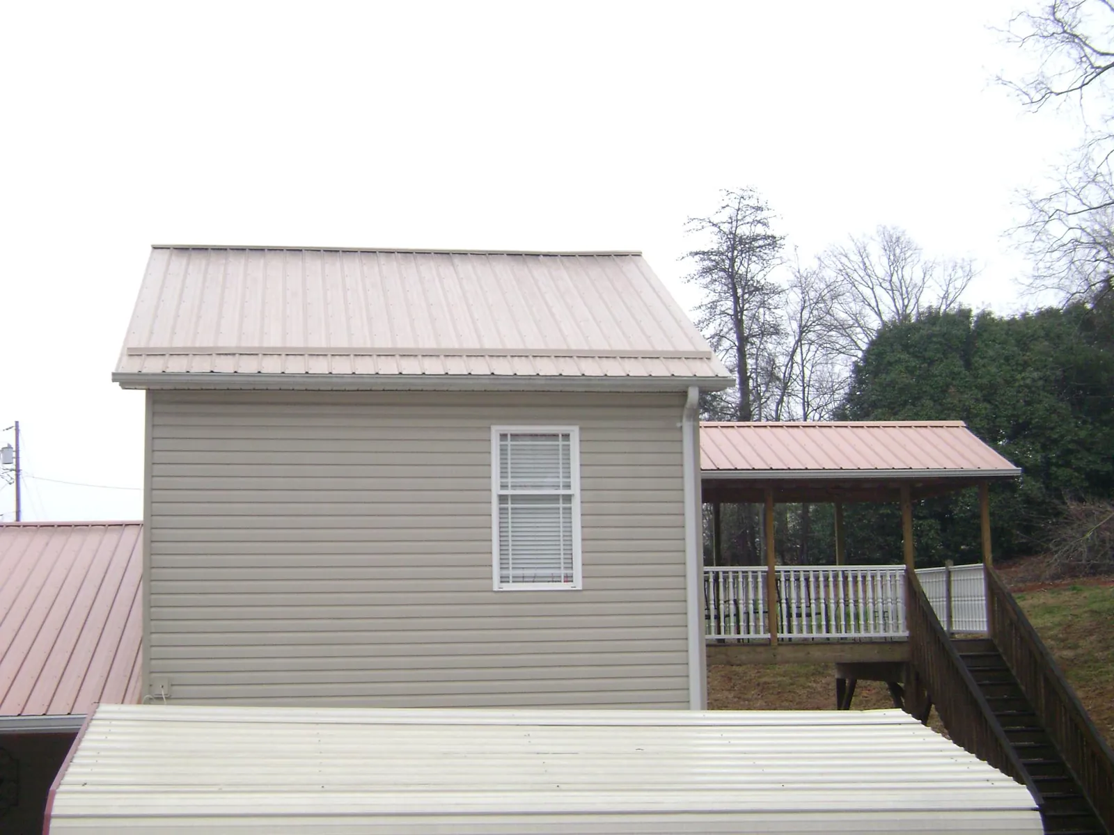 Tan metal roofs on a two story addition and attached porch, from a Roof Replacement job in Pasadena